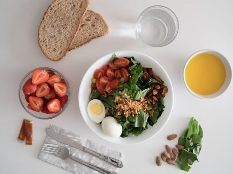 Top view of a nutritious breakfast with salad, eggs, bread, and juice, perfect for a healthy start.